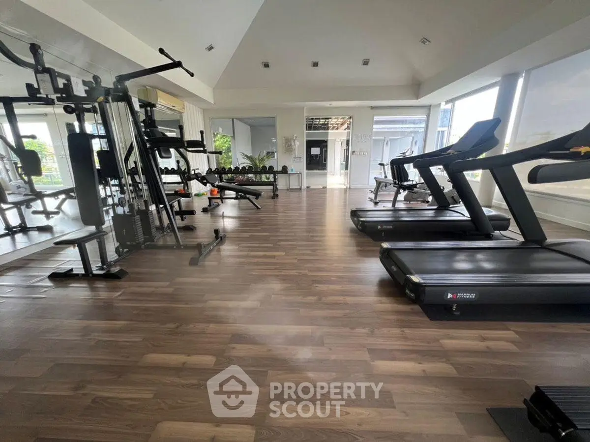 Spacious gym with modern equipment and large windows for natural light.