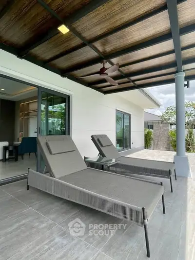 Spacious modern balcony with stylish lounge chairs and ceiling fan, perfect for relaxation.