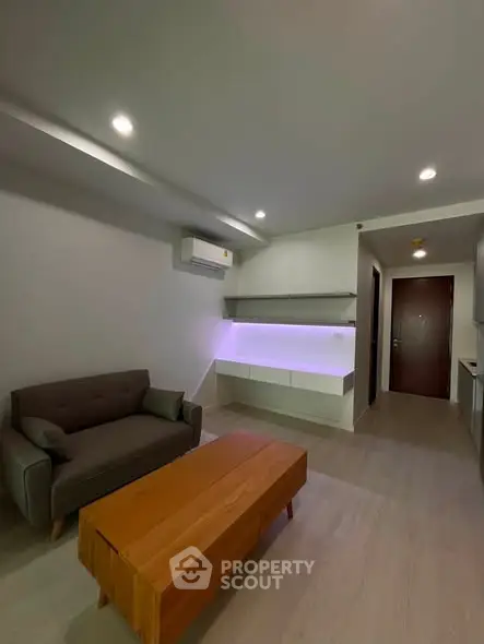 Modern living room with sleek design and ambient lighting, featuring a cozy sofa and wooden coffee table.