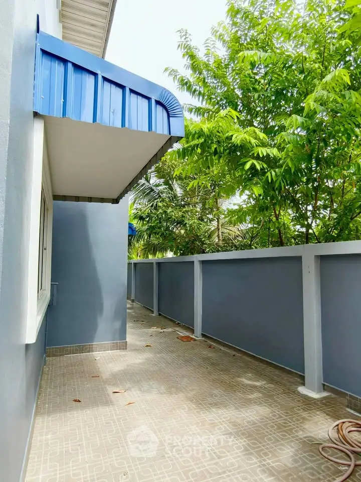 Charming outdoor space with modern blue awning and lush greenery, perfect for relaxation and privacy.
