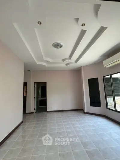 Spacious room with modern ceiling design and large windows for natural light.