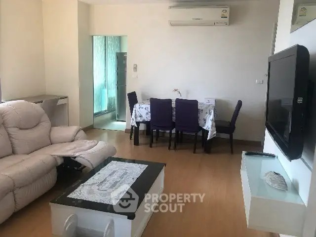 Modern living room with air conditioning and dining area, featuring a sleek wall-mounted TV.