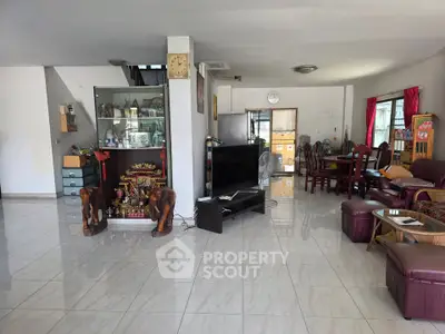 Spacious living room with modern decor and open layout, featuring a large TV and elegant furniture.