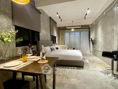 Modern studio apartment with stylish decor and open layout, featuring a cozy bed and dining area.