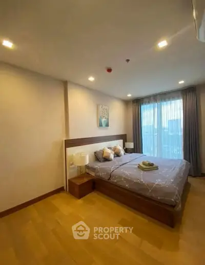 Spacious bedroom with modern decor and large window offering natural light.