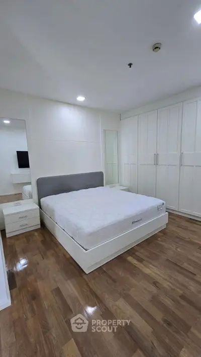 Spacious bedroom with wooden flooring and built-in wardrobes