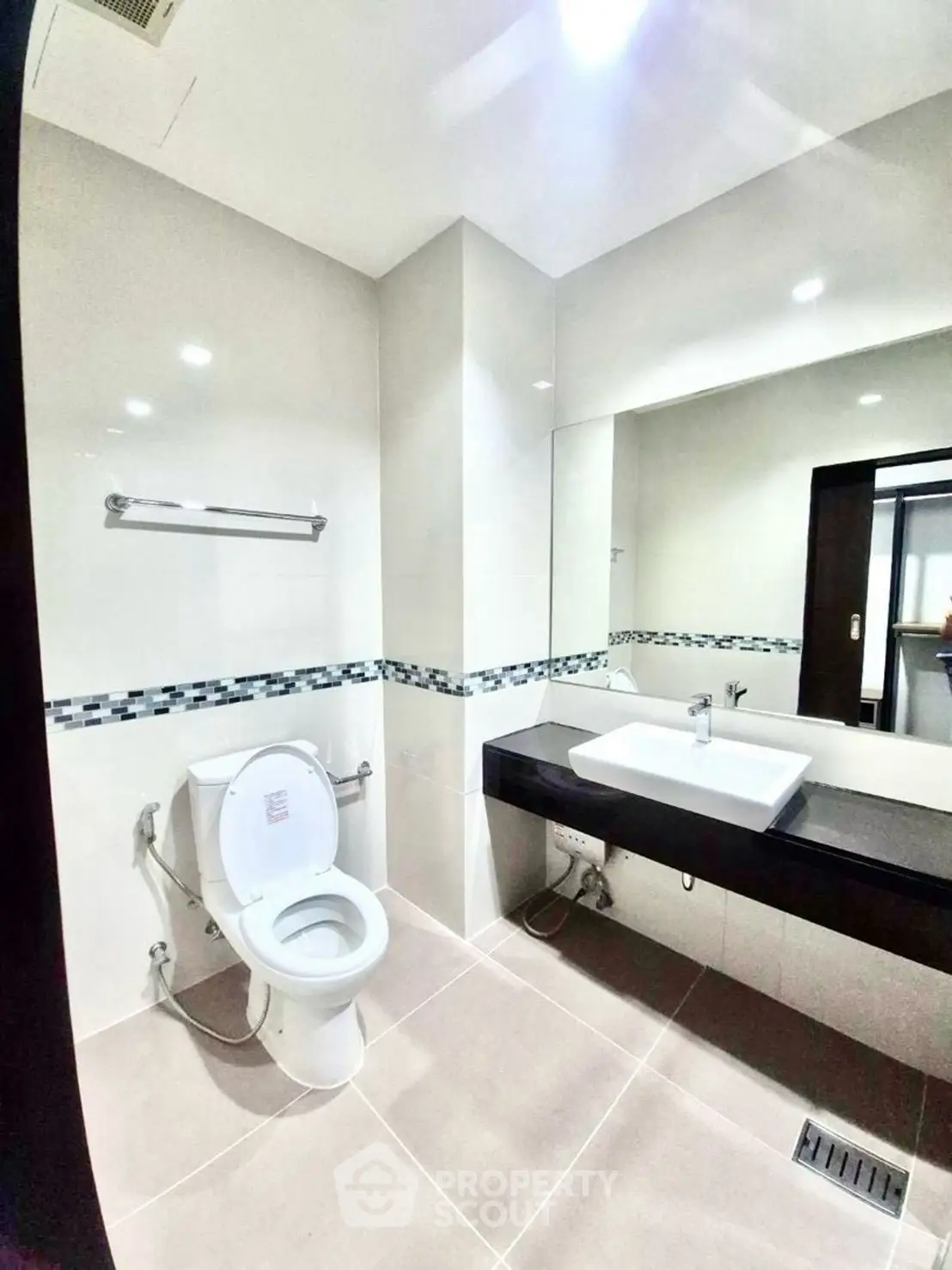 Modern bathroom with sleek fixtures and large mirror in a contemporary home.