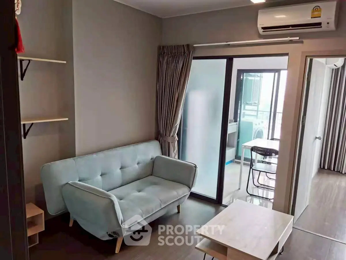 Modern living room with cozy sofa and air conditioning, featuring a glass sliding door to a balcony.