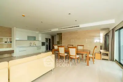 Spacious open-plan living and dining area with modern kitchen in luxury apartment.