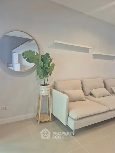 Modern living room with stylish beige sofa and decorative plant, perfect for cozy relaxation.