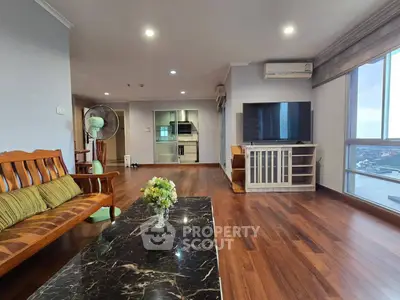 Spacious living room with wooden flooring and river view, featuring modern furniture and large windows.