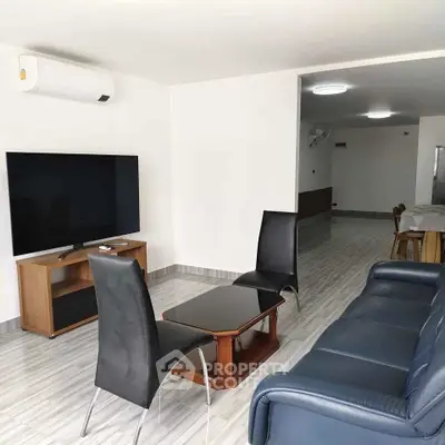 Modern living room with sleek furniture and large TV, perfect for relaxation and entertainment.