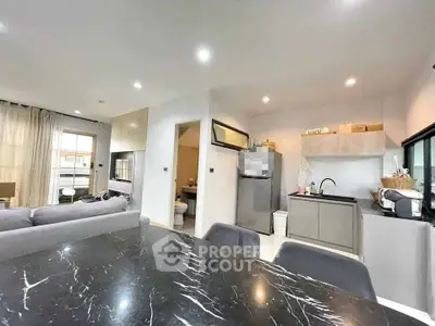Modern open-plan living room and kitchen with sleek design and marble dining table.