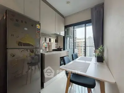 Modern kitchen with dining area and city view, featuring sleek cabinetry and natural light.