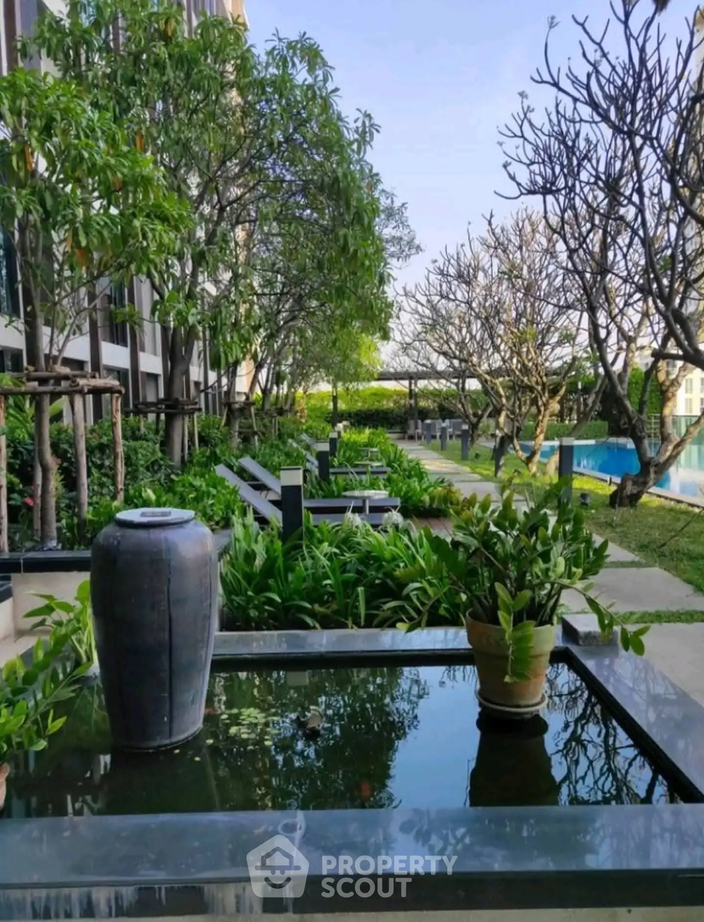 Luxurious garden view with serene water feature and lush greenery in modern residential complex.