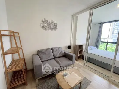 Modern living room with cozy sofa and view into a bright bedroom, featuring stylish decor and natural light.