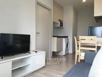 Modern apartment living room with TV, dining set, and kitchen appliances.