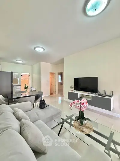 Spacious modern living room with sleek furniture and large TV, perfect for relaxation.