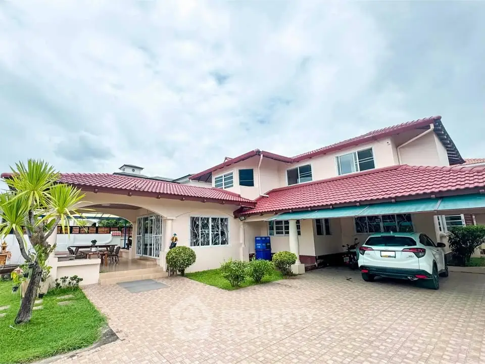 Spacious two-story house with red roof, large driveway, and lush garden in a serene neighborhood.