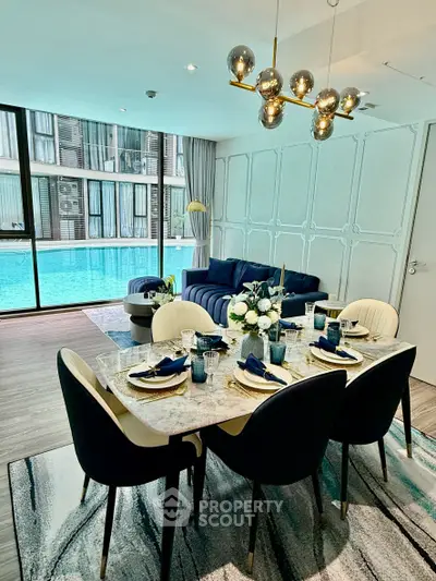 Luxurious living room with pool view, elegant dining setup, and modern decor in a high-end apartment.