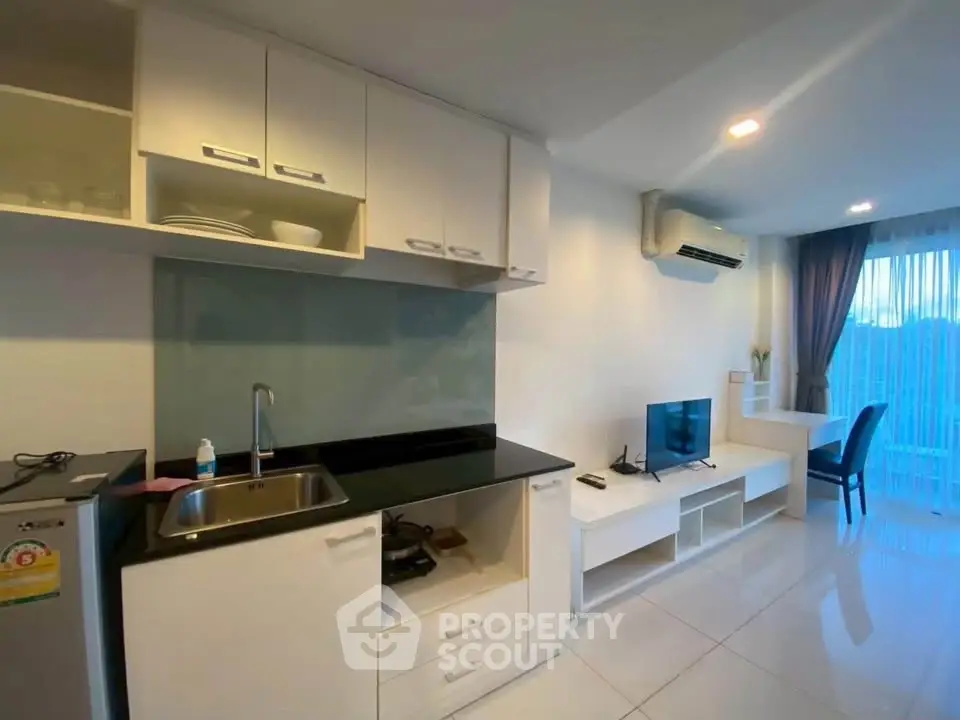 Modern studio apartment with sleek kitchen and cozy living area, featuring large windows and natural light.