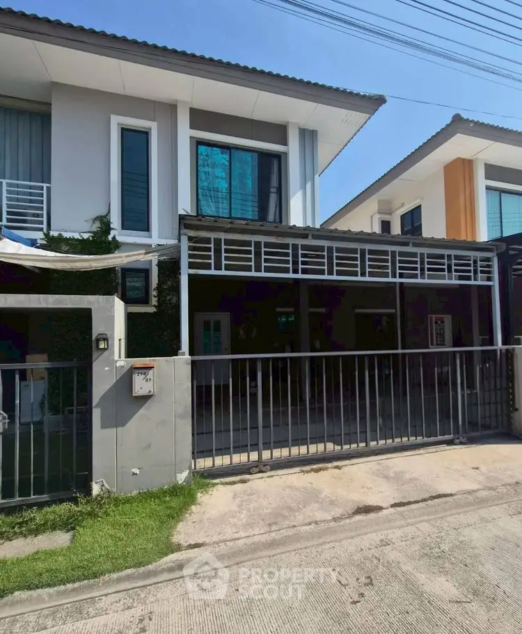Modern two-story house with gated driveway and contemporary design.