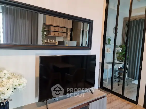 Modern living room with sleek TV and stylish decor, featuring a glimpse into a cozy study area.