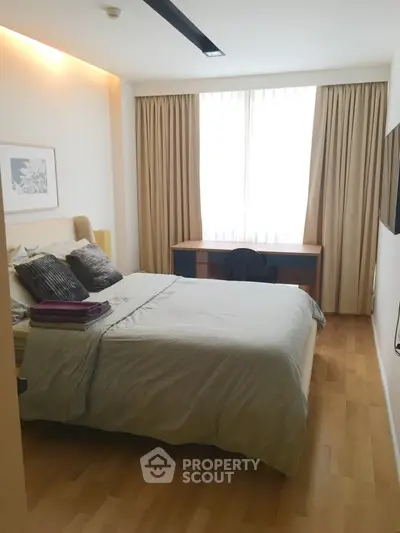 Cozy bedroom with natural light, modern furnishings, and wooden flooring, perfect for relaxation.