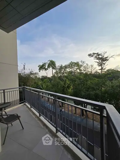 Spacious balcony with scenic view of lush greenery and clear sky, perfect for relaxation.