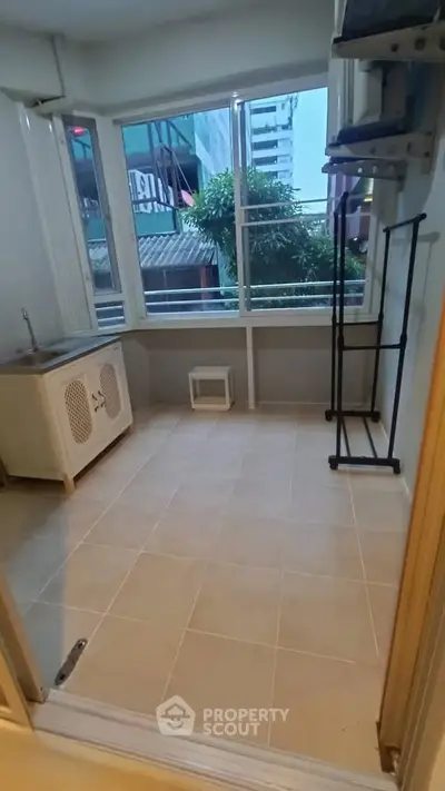 Bright utility room with large windows and tiled floor, perfect for laundry or storage.