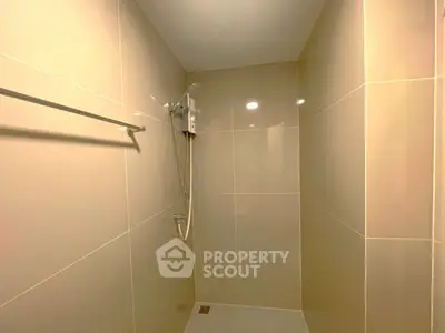 Modern minimalist bathroom with sleek beige tiles and shower area.