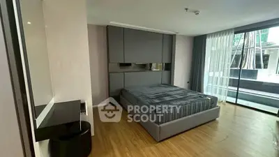 Spacious modern bedroom with large windows and sleek furnishings in a luxury apartment.