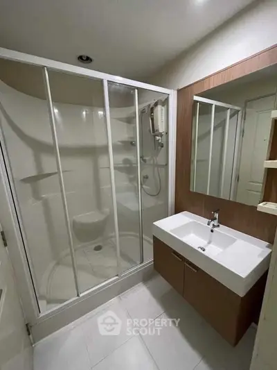 Modern bathroom with glass shower enclosure and sleek vanity in contemporary apartment.
