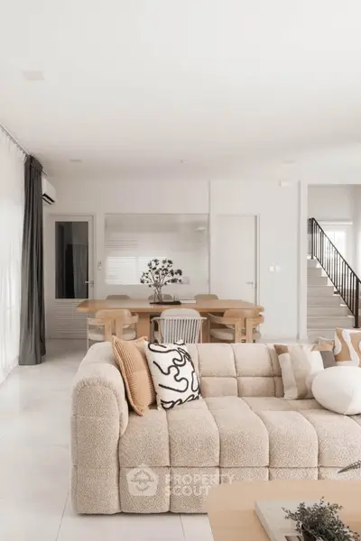Elegant living room with modern beige sofa and stylish dining area in open layout