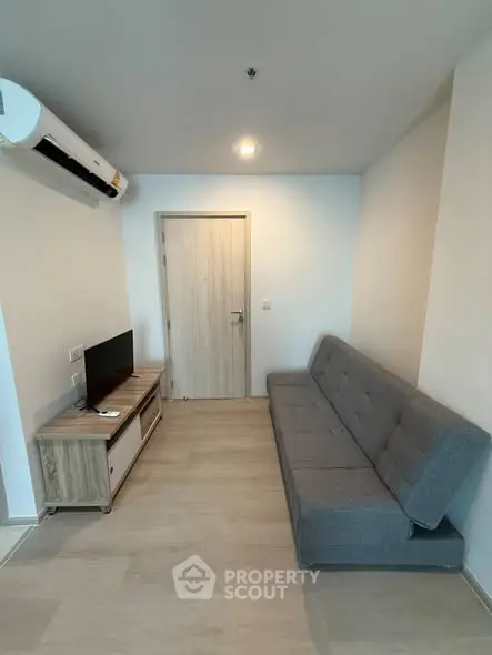 Modern living room with sleek gray sofa and minimalist TV stand, perfect for cozy relaxation.