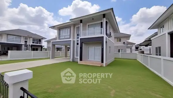 Modern two-story house with spacious lawn and driveway under a clear blue sky.