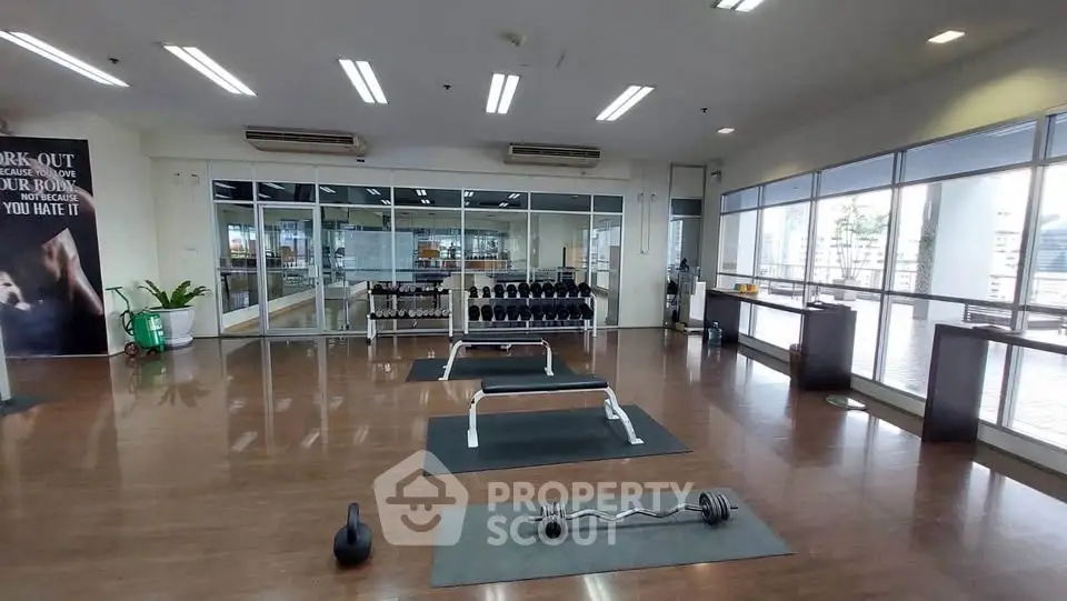 Spacious gym with modern equipment and city view, perfect for fitness enthusiasts.