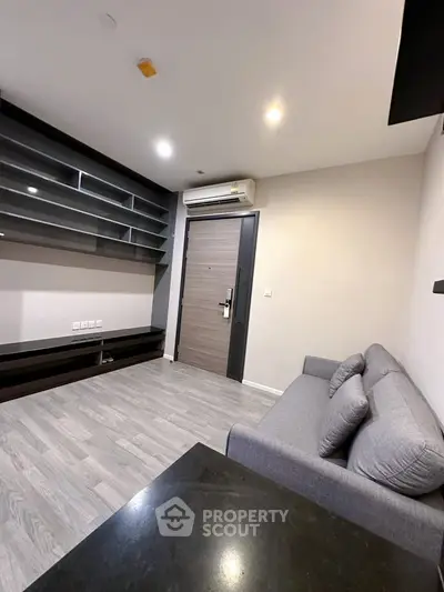 Modern living room with sleek shelving and cozy gray sofa, featuring stylish flooring and air conditioning.