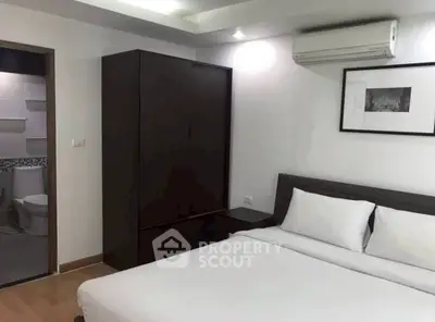 Modern bedroom with ensuite bathroom, featuring sleek furniture and air conditioning.