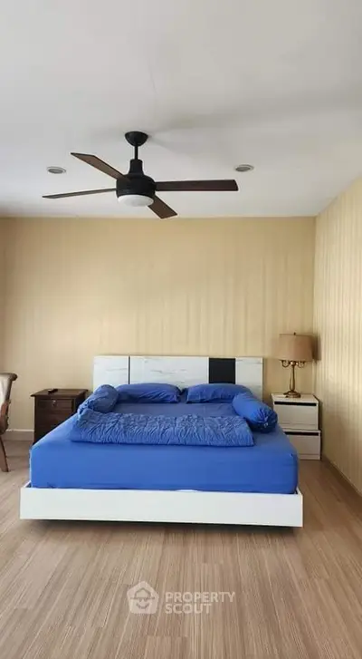 Spacious bedroom with modern decor and ceiling fan, featuring a comfortable bed and stylish furnishings.