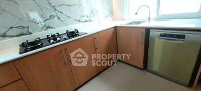 Modern kitchen with gas stove and dishwasher, sleek cabinetry, and marble backsplash.