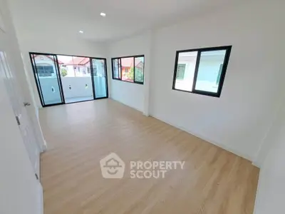 Spacious and bright room with large windows and wooden flooring, perfect for modern living.