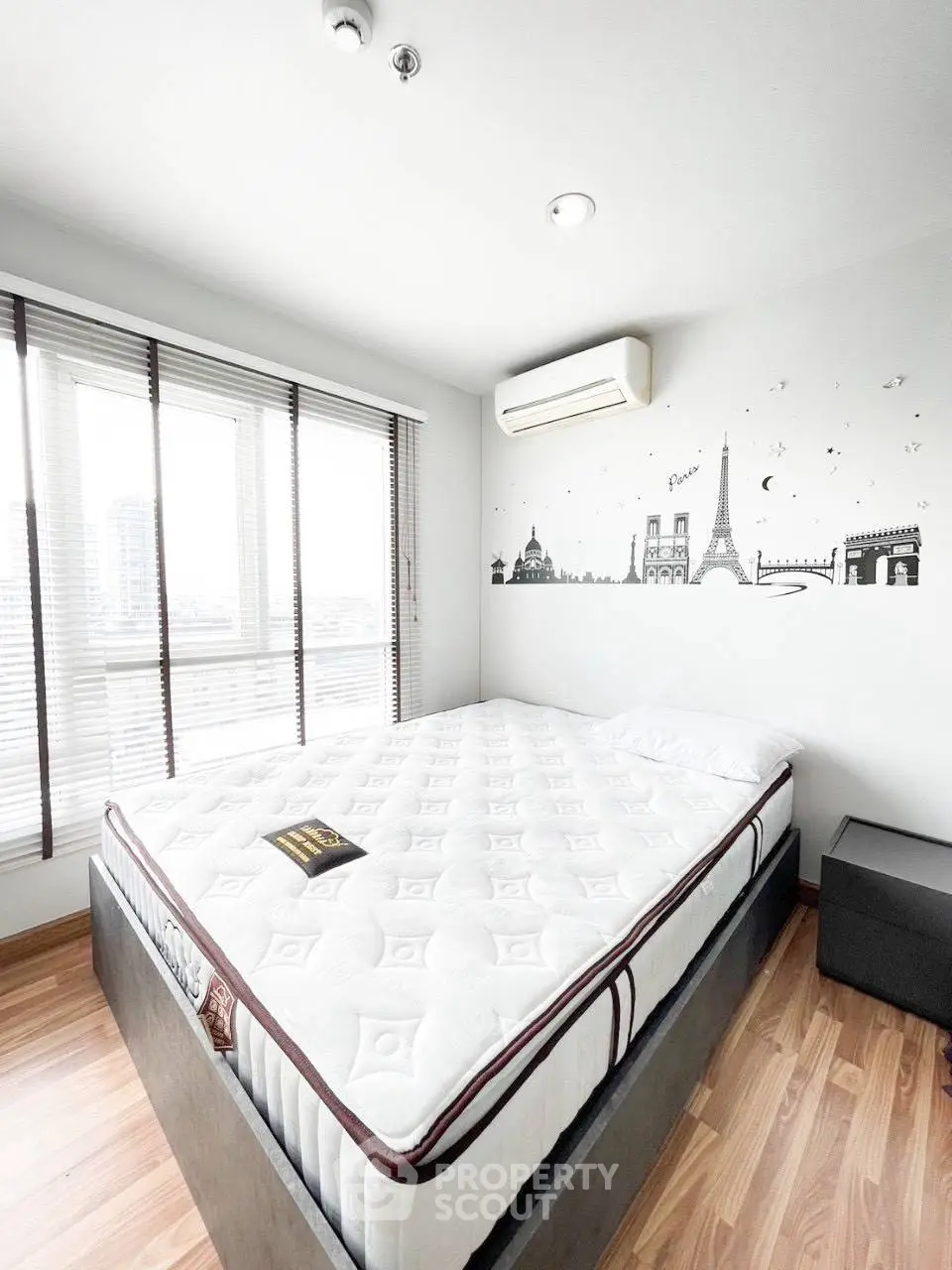 Bright bedroom with city view and stylish wall art in modern apartment.