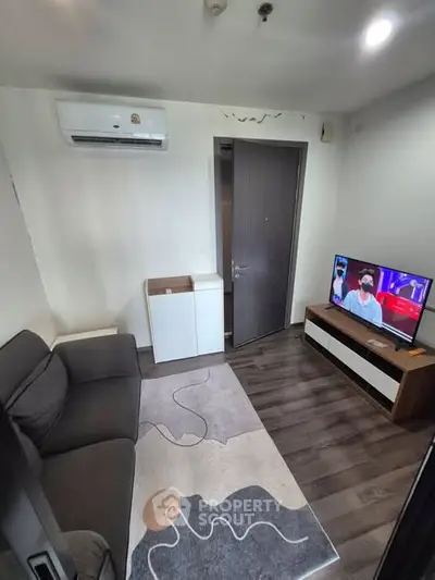 Cozy living room with modern decor, featuring a comfortable sofa, stylish rug, and wall-mounted air conditioner.
