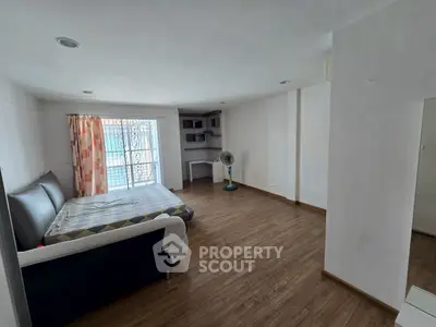Spacious bedroom with wooden flooring and natural light, featuring a cozy bed and modern decor.