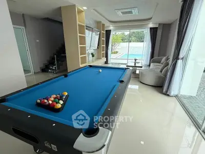 Luxurious living room with pool table and view of private pool, perfect for entertainment and relaxation.