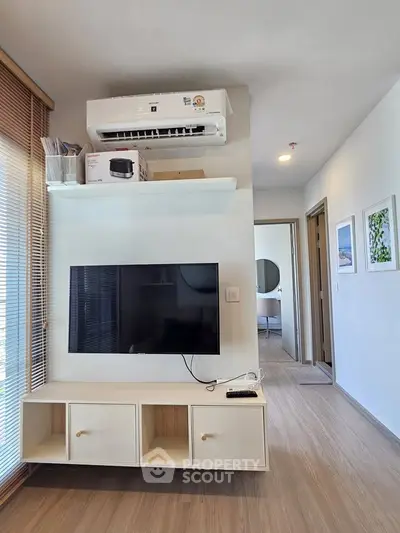 Modern living room with sleek TV setup and air conditioning in a stylish apartment.