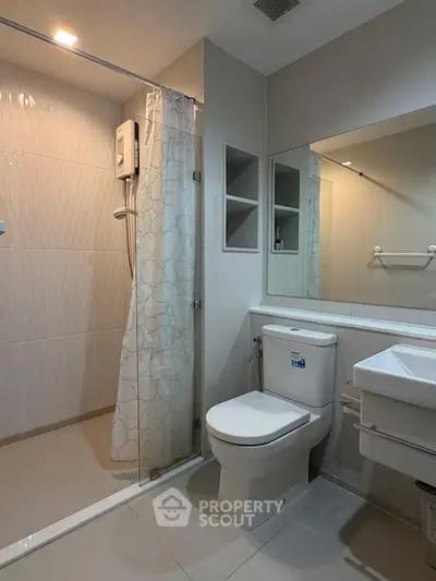 Modern bathroom with glass shower and sleek fixtures in contemporary apartment.