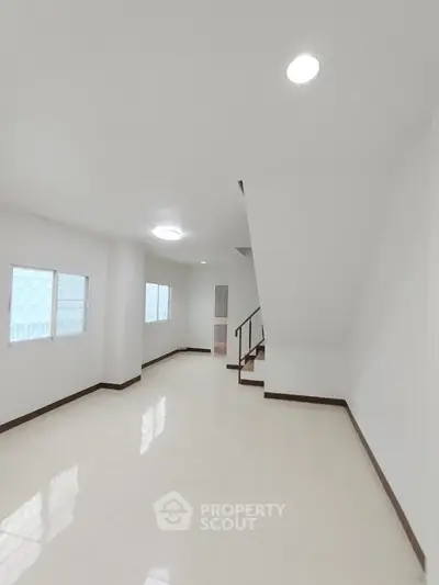 Spacious minimalist interior with staircase and natural light, perfect for modern living.