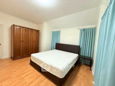 Spacious bedroom with wooden wardrobe and comfortable bed, perfect for relaxation.